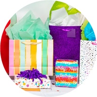 A group of gift bags stuffed with tissue paper behind wrapped gifts