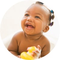 A smiling baby holding a toy duck